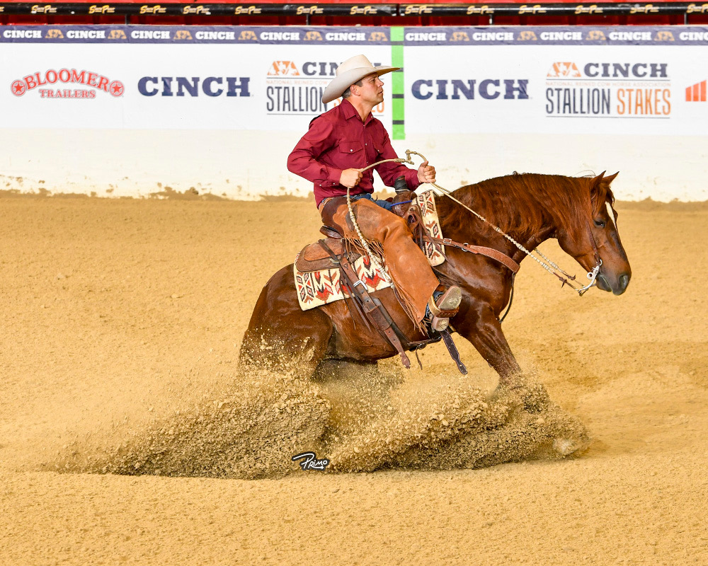 Trevor Haught riding a sorrel cow horse through a sliding stop in the arena at the NRCHA Stallion Stakes