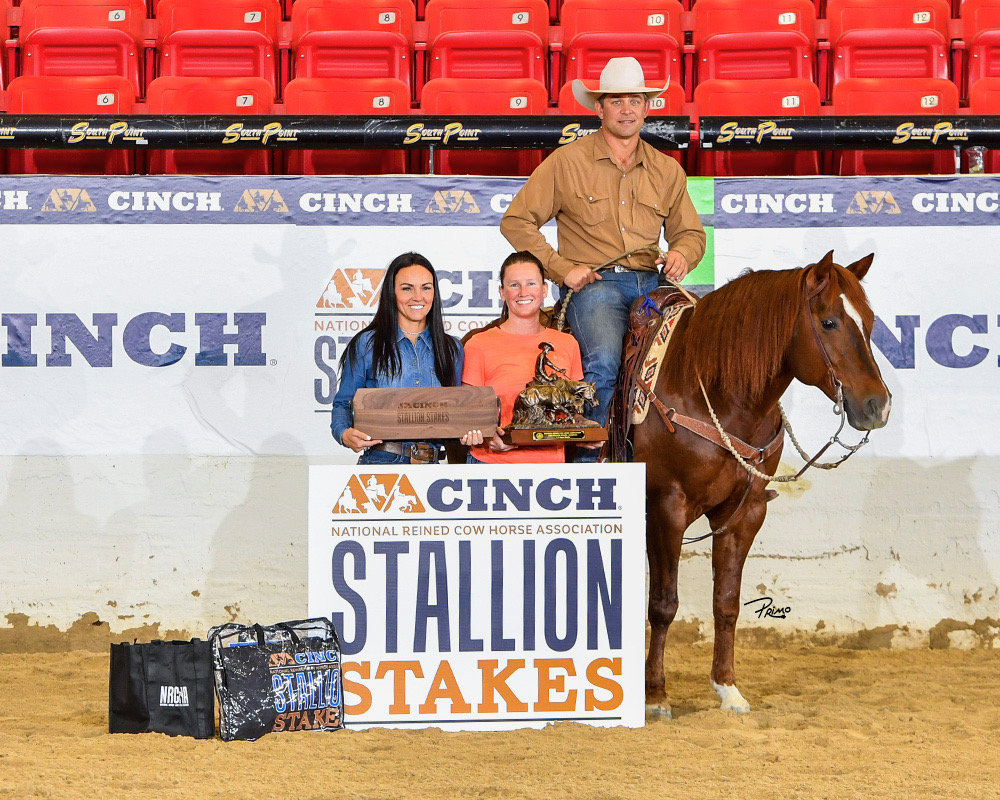 Trevor Haught mounted on a sorrel horse with two women holding trophies in the winner's circle at the NRCHA Stallion Stakes